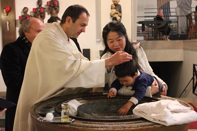 Pfarrer Martin tauft ein Baby in Neufünfhaus