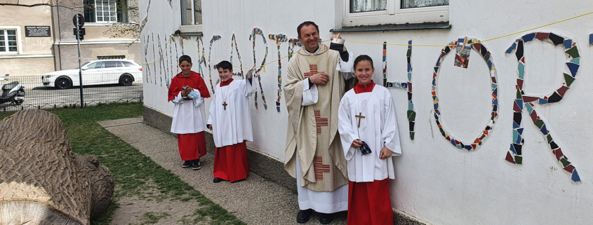 Pfarrer Martin und Ministrant/innen begutachten die Fotos