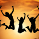 Fünf Menschen springen vor einem Sonnenuntergang in die Luft