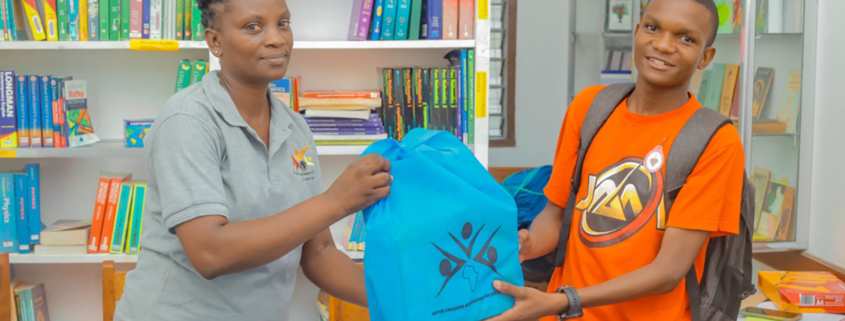 Eine Mitarbeiterin der Stiftung überreicht einem Kind ein Schulpaket