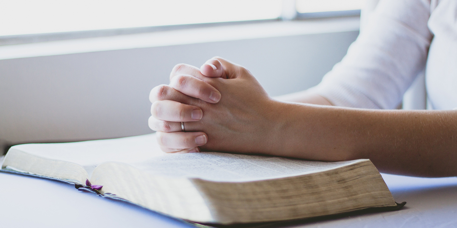 Gefaltete Hände auf einer Bibel