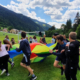 Kinder spielen mit einem großen Tuch auf einer Wiese