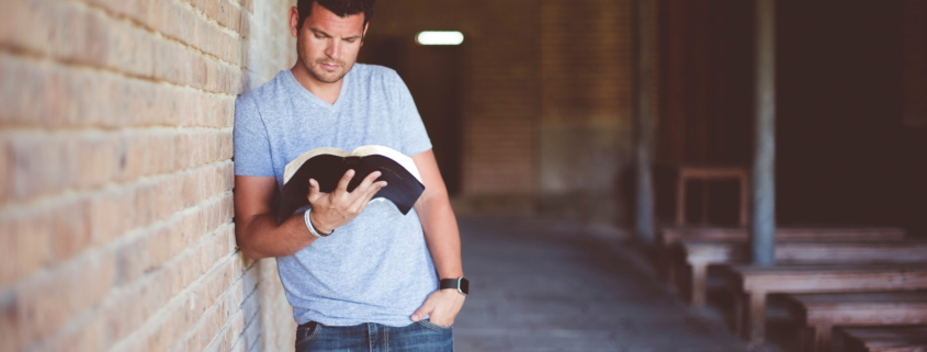 Ein junger Mann, der die Bibel im Stehen liest