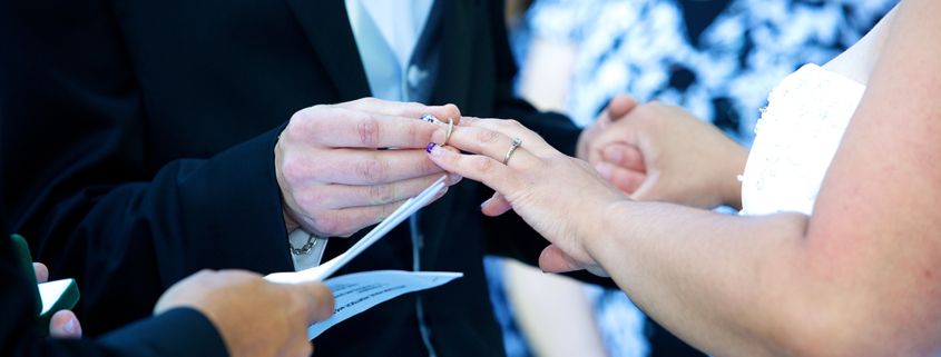 Ein Bräutigam steckt der Braut den Ring an