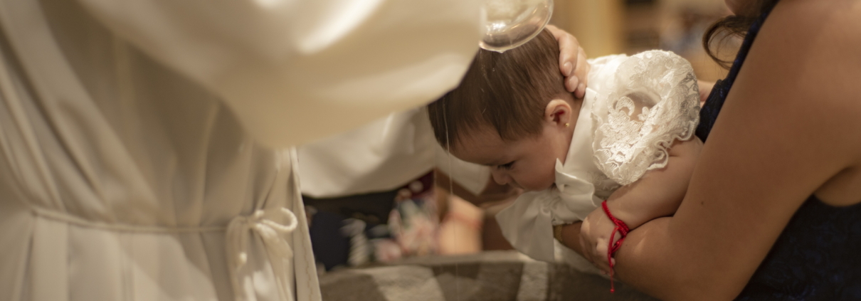 Ein Baby, das über einem Taufbecken getauft wird