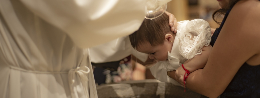 Ein Baby, das über einem Taufbecken getauft wird
