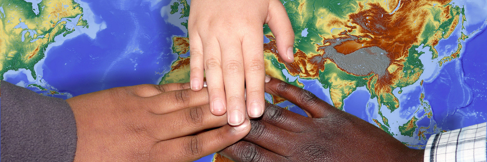 Eine weiße, eine braune und eine schwarze Hand auf einer Weltkarte