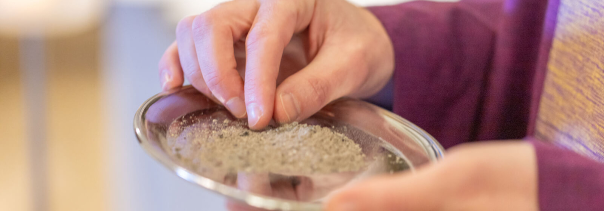 Ein Priester hält ein Tablett mit Asche in den Händen