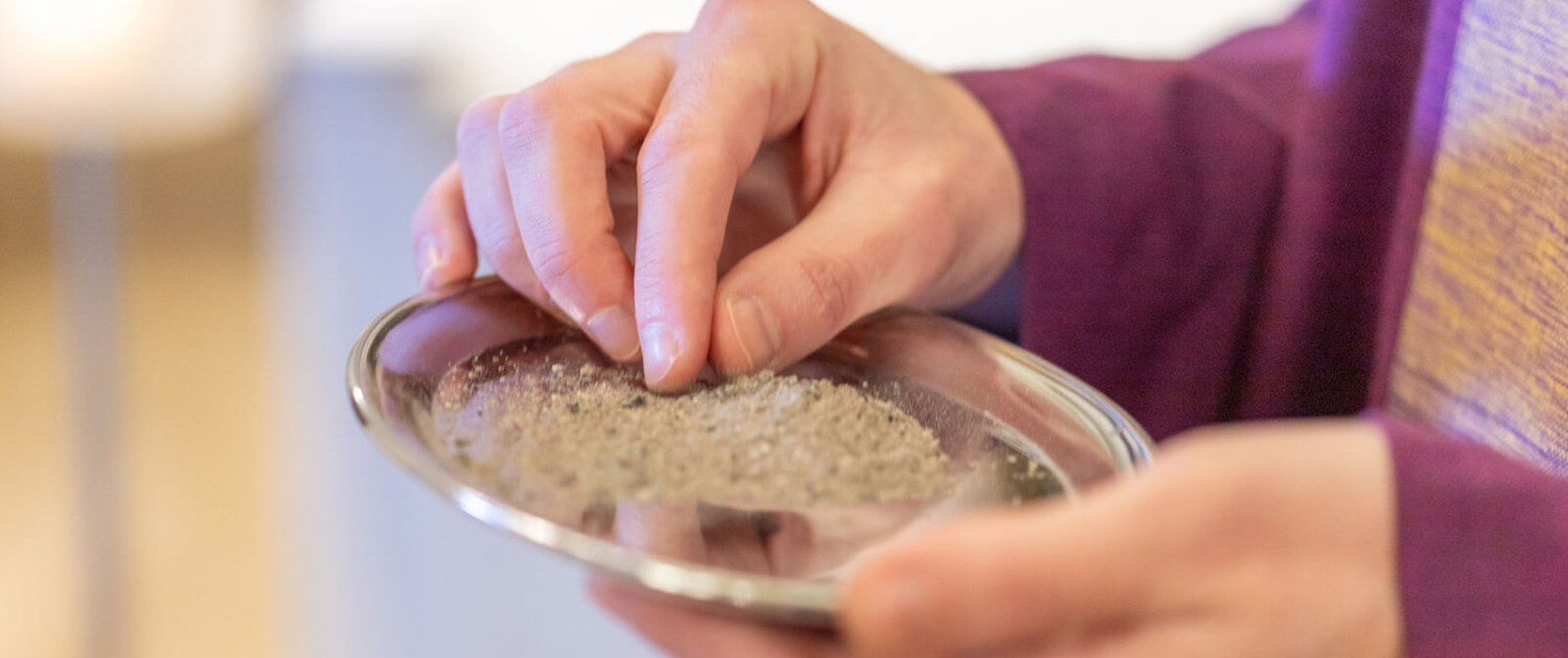 Aschenkreuzspende Ein Priester hält ein Tablett mit Asche in den Händen