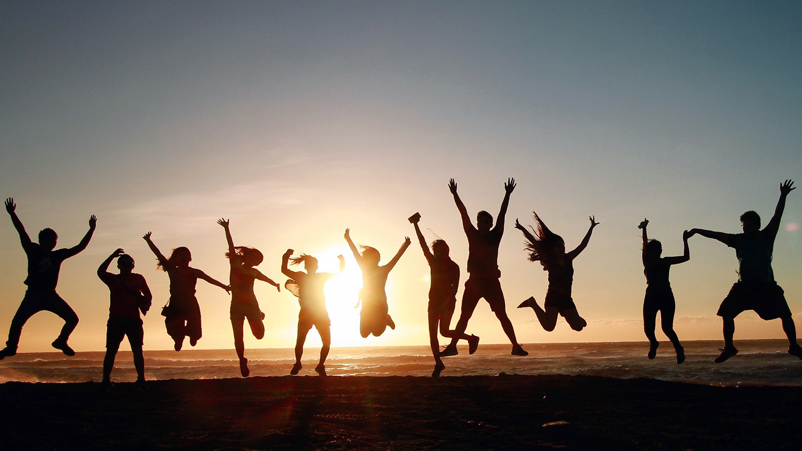 Junge Menschen springen vor einem Sonnenuntergang in die Luft