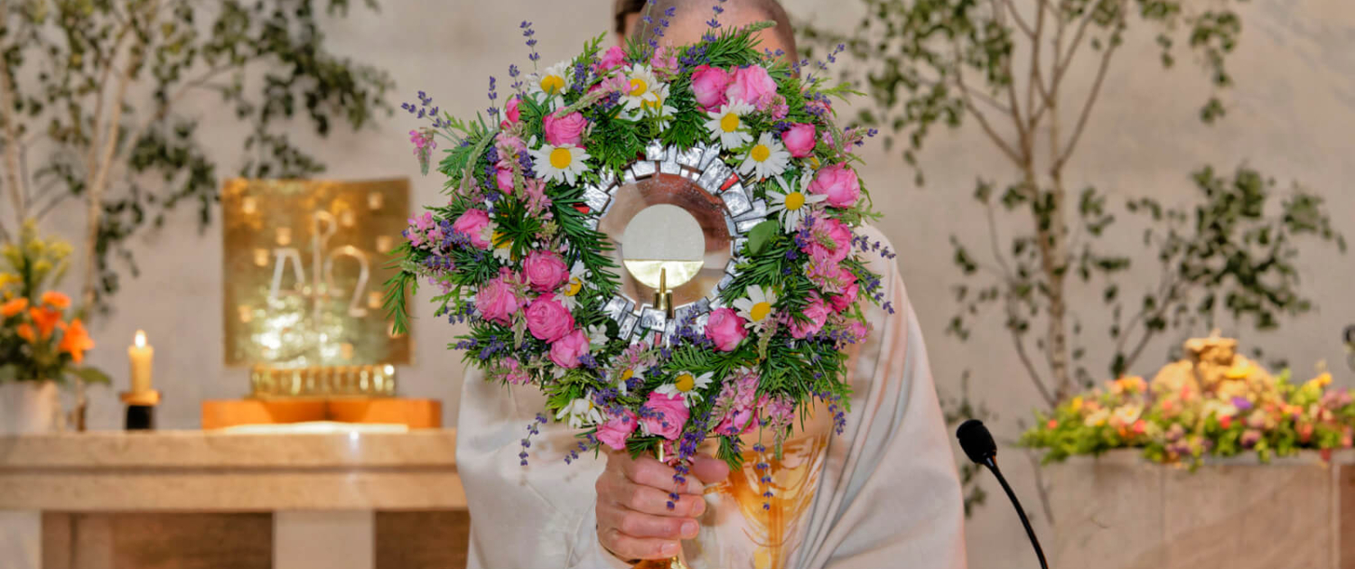 Fronleichnam 2023 Schönbrunn-Vorpark Ein Priester hält eine blumengeschmückte Monstranz in der Kirche Schönbrunn-Vorpark