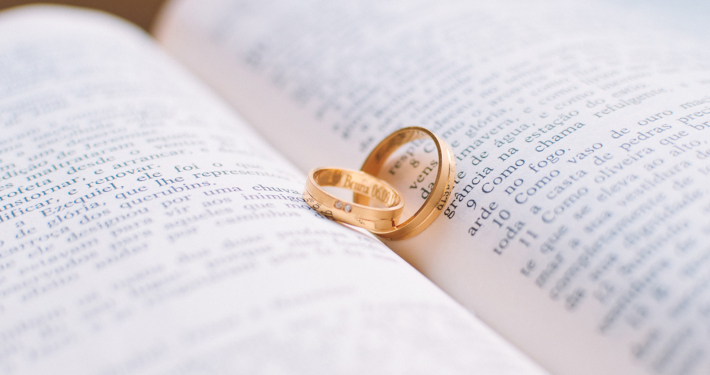 Zwei rotgoldene Eheringe auf einer Bibel in italienischer Sprache