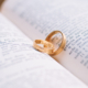 Zwei rotgoldene Eheringe auf einer Bibel in italienischer Sprache