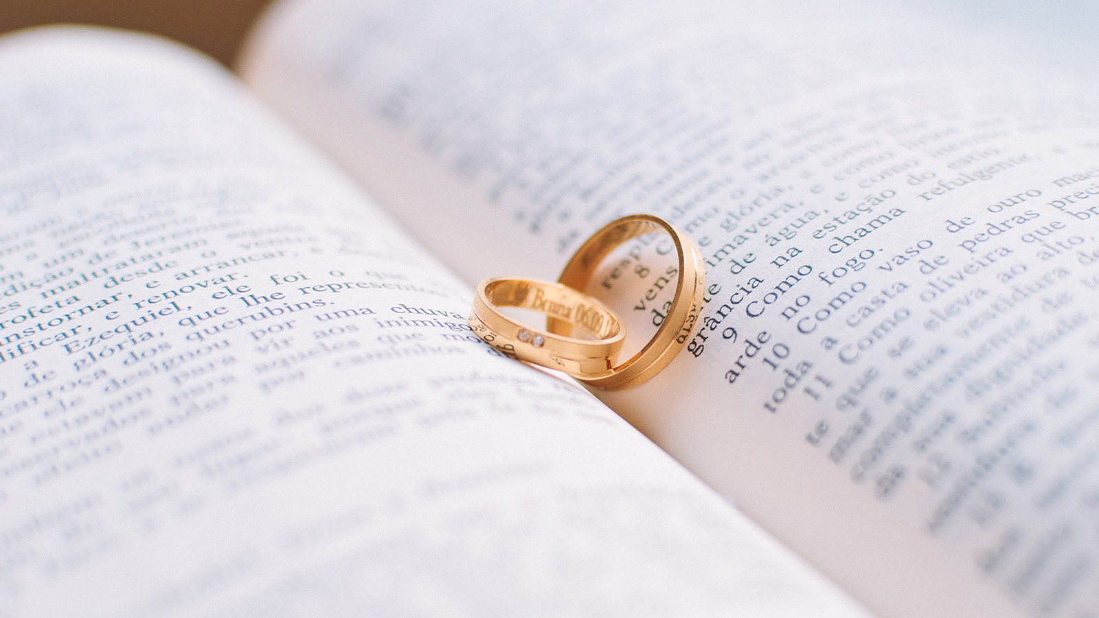 Zwei rotgoldene Eheringe auf einer Bibel in italienischer Sprache