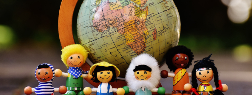 Ein kleiner Globus und sechs Holzfiguren, die verschiedene Ethnien darstellen