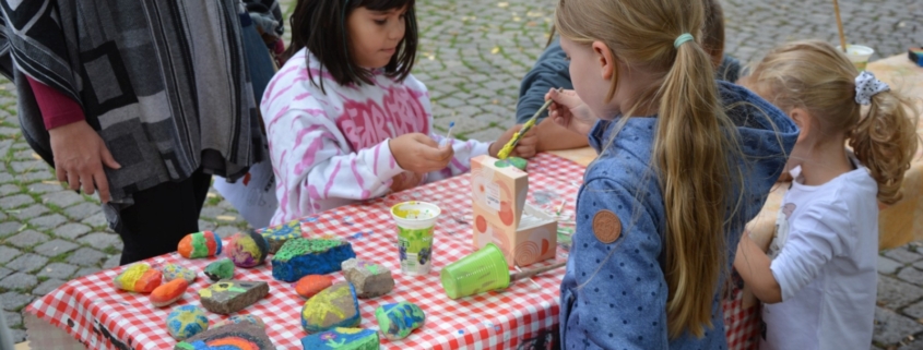 Kinder bemalen Steine mit Pinsel und Farbe