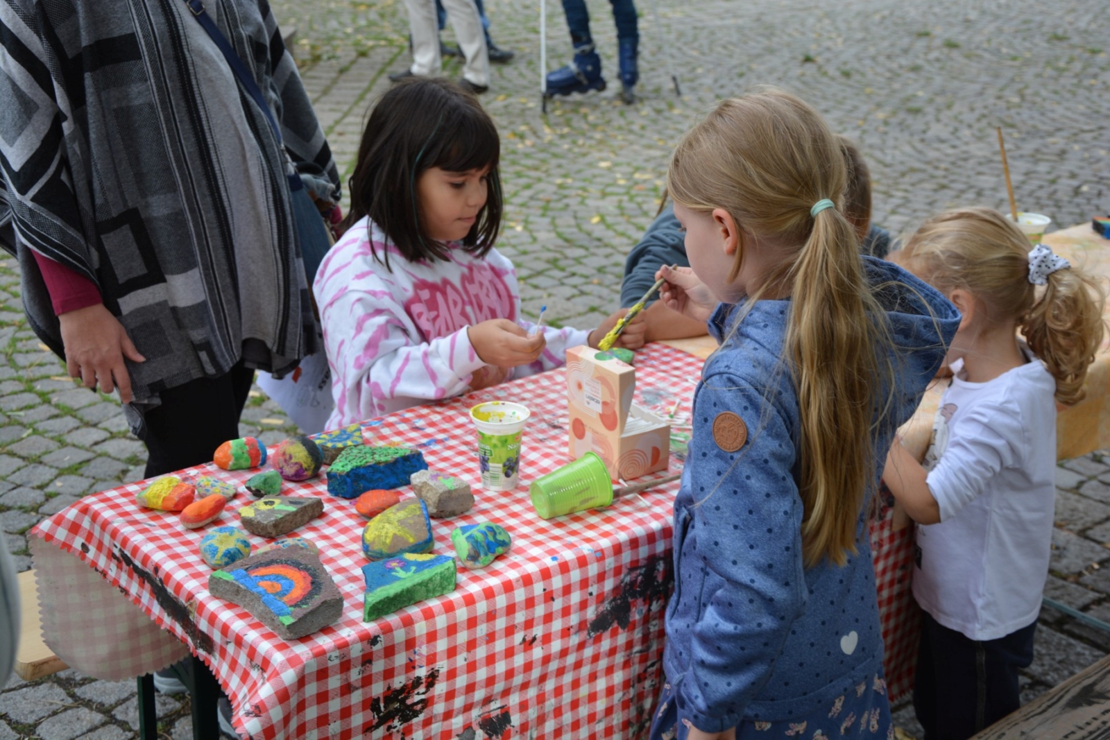 Kinder bemalen Steine mit Pinsel und Farbe