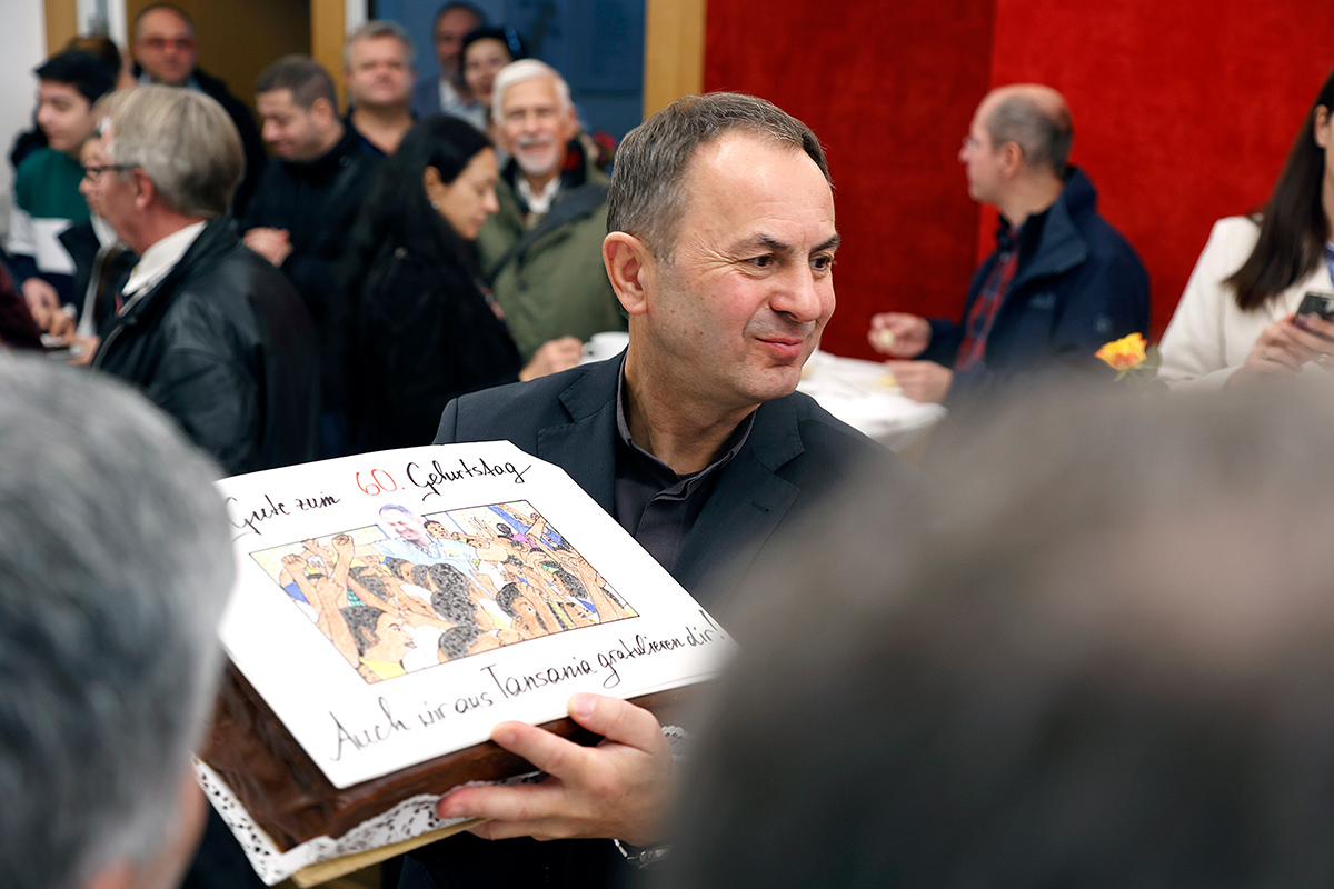 Pfarrer Martin zeigt eine Geburtstagstorte mit Glückwünschen aus Tansania her