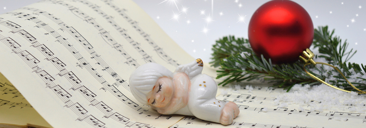 Eine Christbaumkugel und ein Porzellanengel auf einem Notenbuch