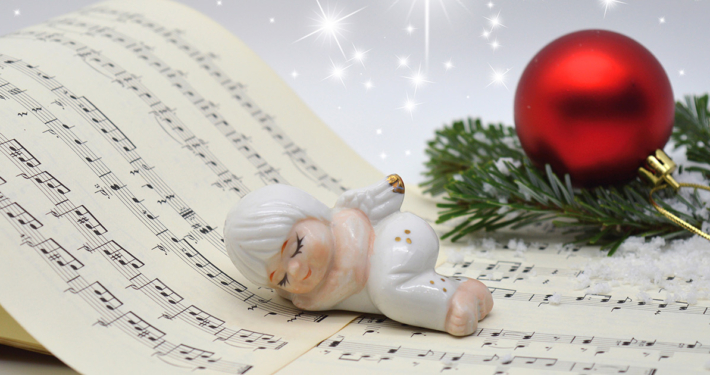 Eine Christbaumkugel und ein Porzellanengel auf einem Notenbuch