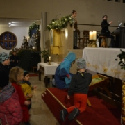 Kinder legen Strohhalme in die Krippe am Altar in Neufünfhaus