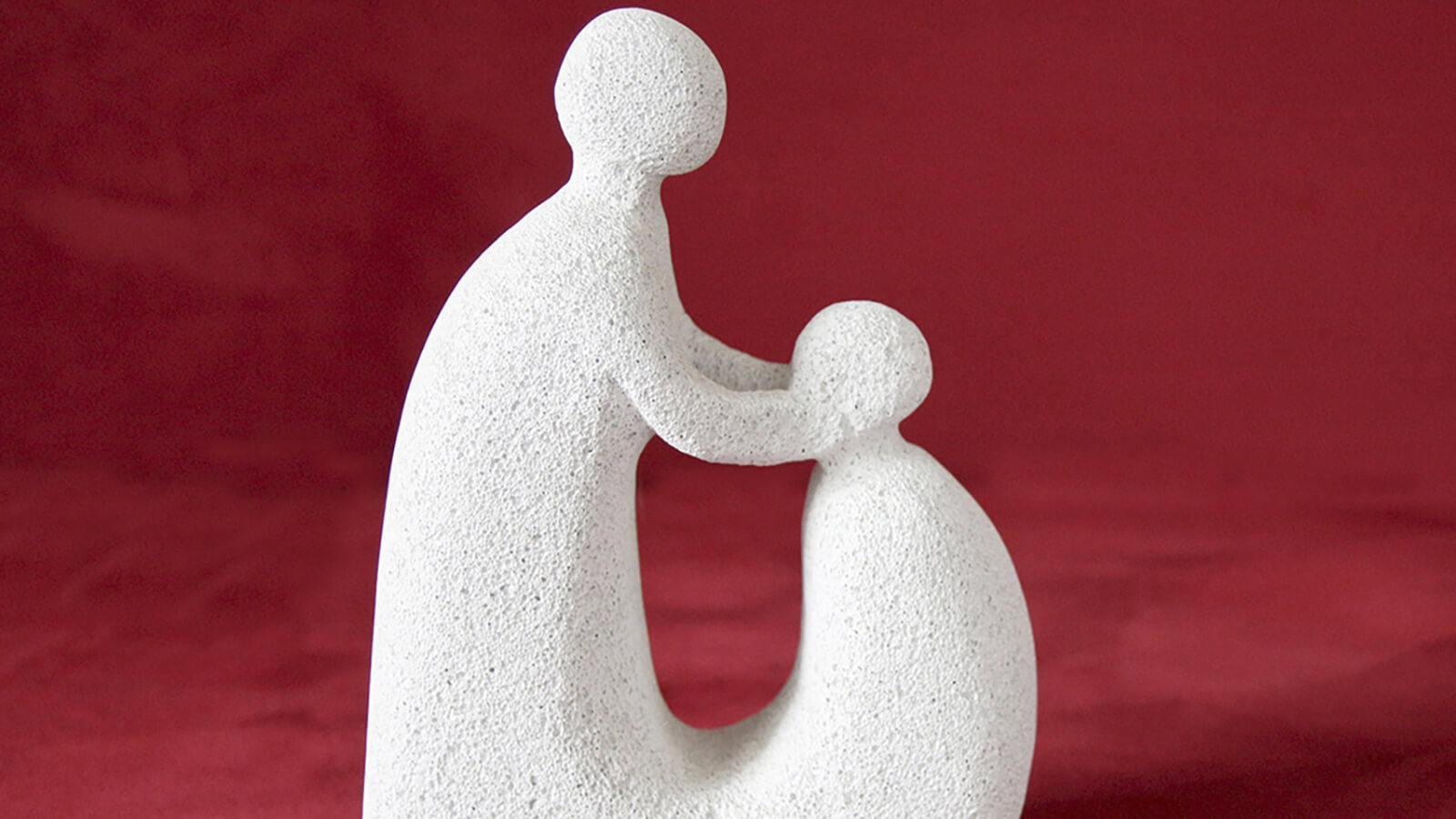 Segen Eine Stein-Skulptur mit 2 Personen, von denen die eine die andere segnet