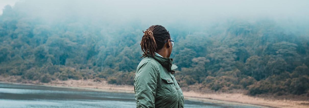 eine Frau dreht sich um und blickt auf einen See im Nebel