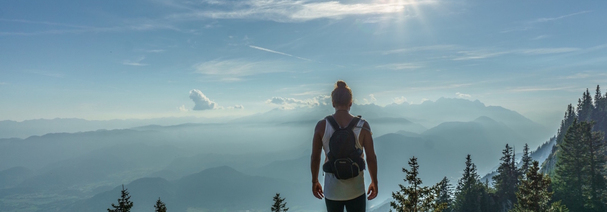 Eine Frau in Sportkleidung steht auf einem Aussichtspunkt in der Natur