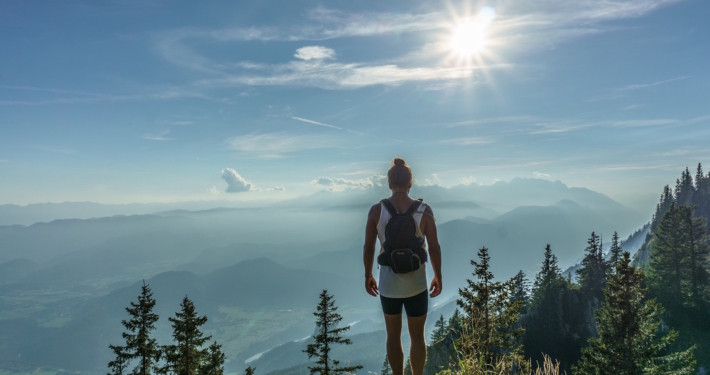 Eine Frau in Sportkleidung steht auf einem Aussichtspunkt in der Natur