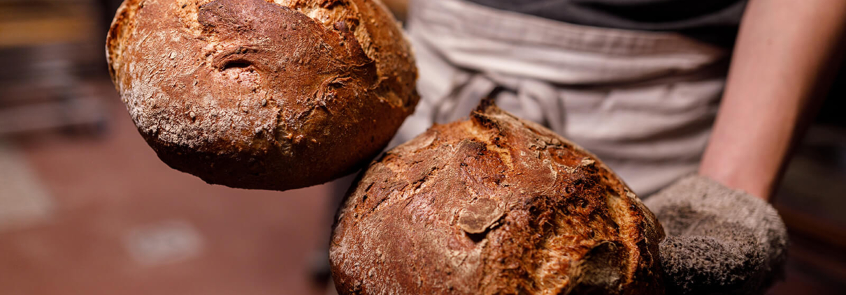Ein Bäcker präsentiert zwei Brotlaibe