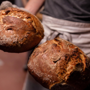 Ein Bäcker präsentiert zwei Brotlaibe