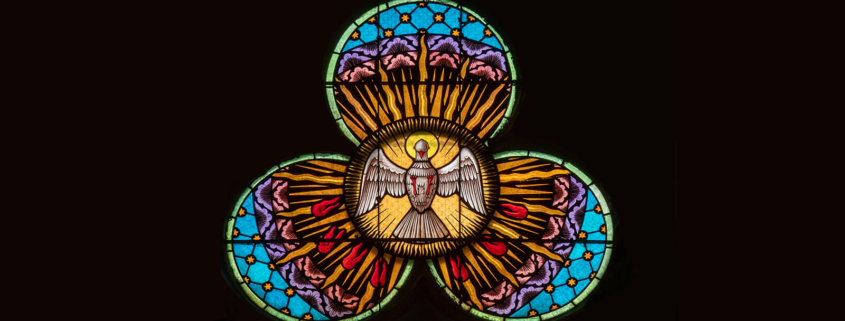 Ein Kirchenfenster in Blütenform, das den Heiligen Geist als Taube zeigt