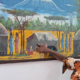 Eine afrikanische Frau zeigt auf ein Massai-Gemälde