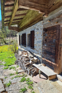Ein altes Bauernhaus mit einer Bank und Brennholz davor
